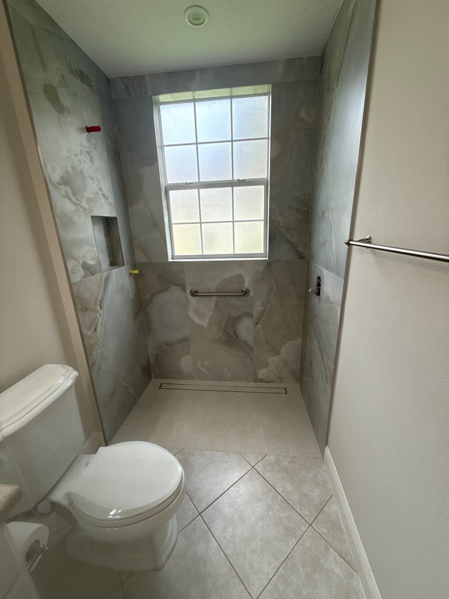 Completed marble-look shower with a linear drain from the Black Gold project gallery